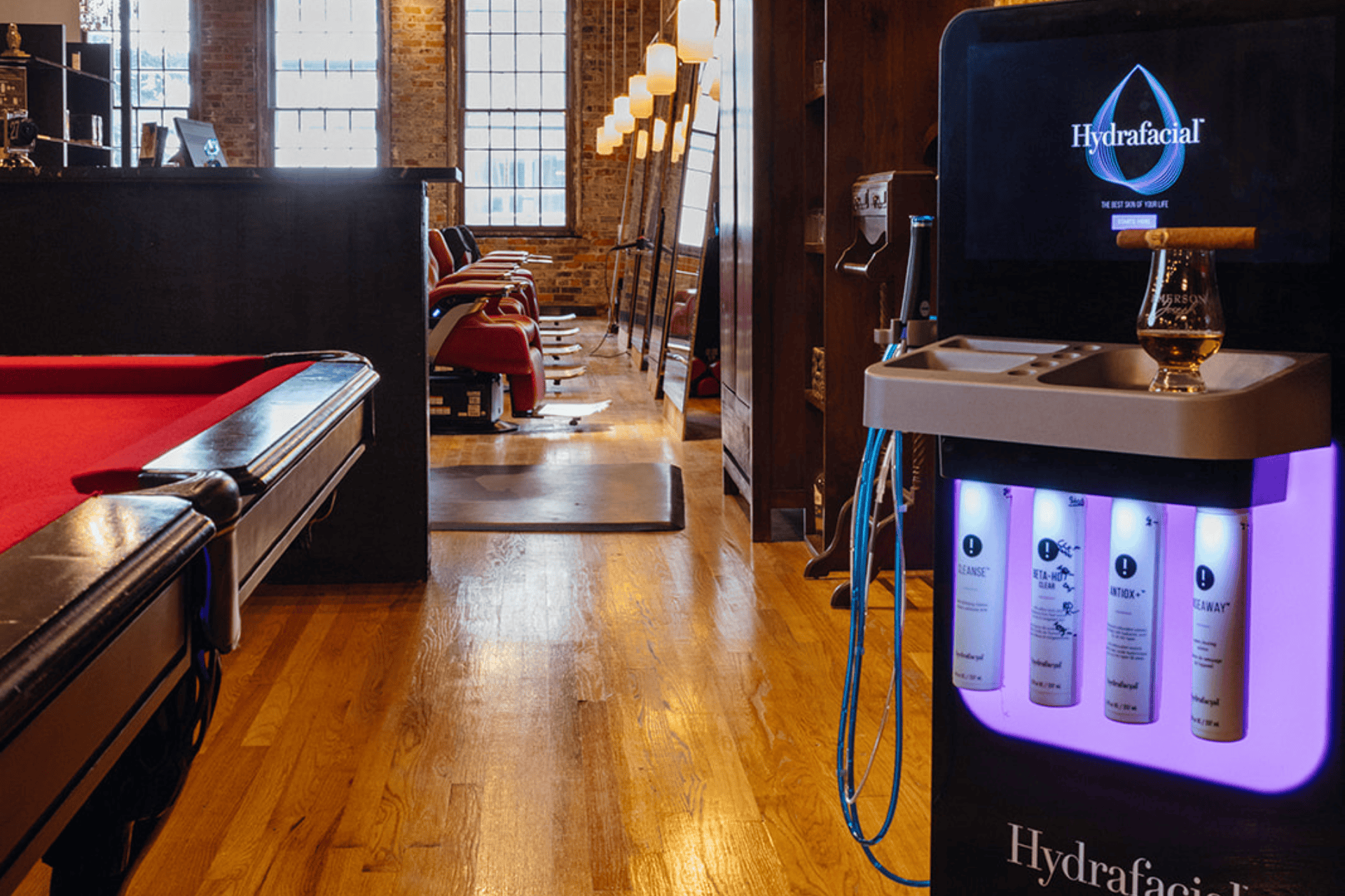 A Hydrafacial treatment machine next to a pool table set up in a luxury barbershop