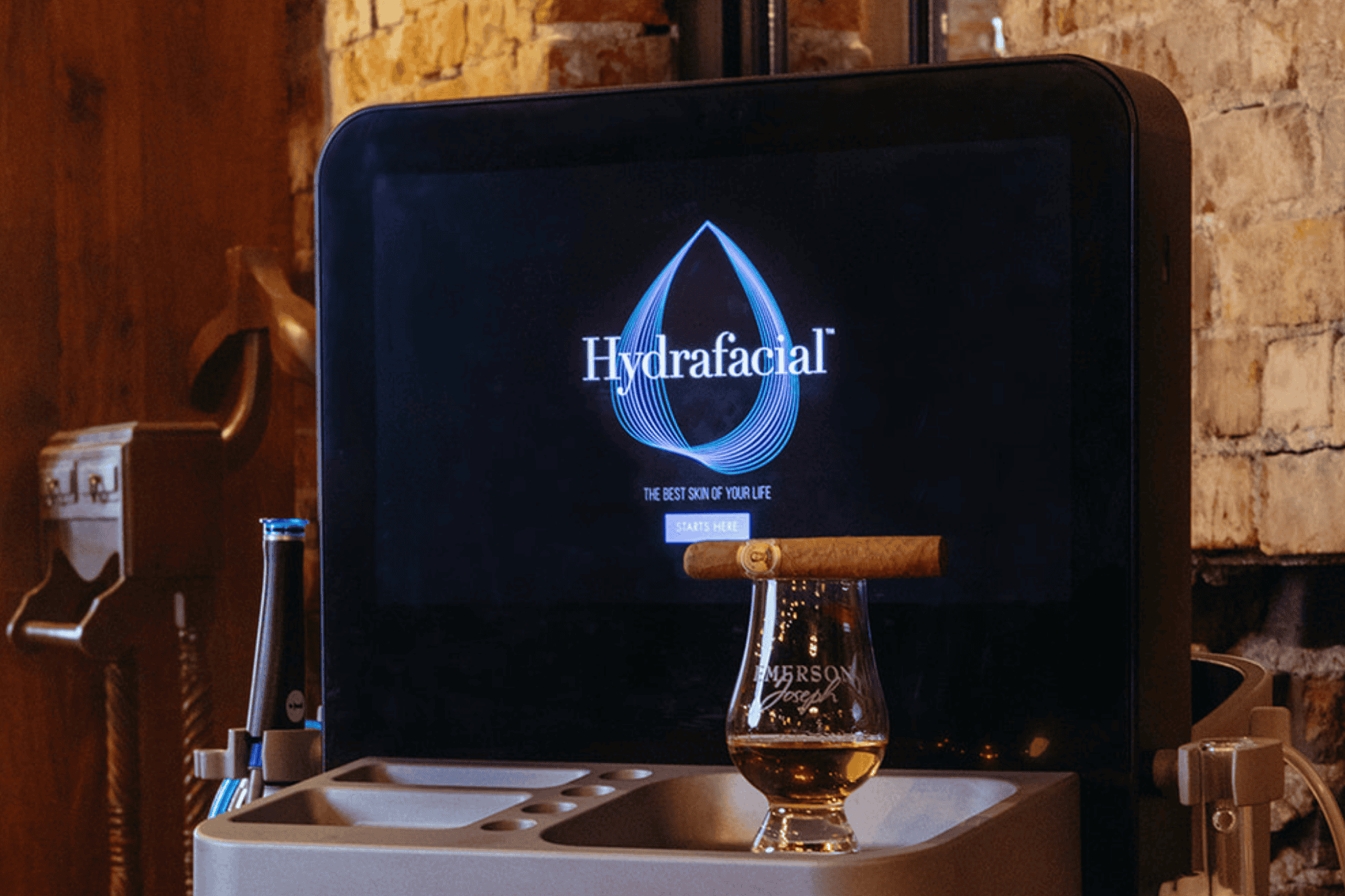 A Hydrafacial machine with a glass of whiskey and a cigar