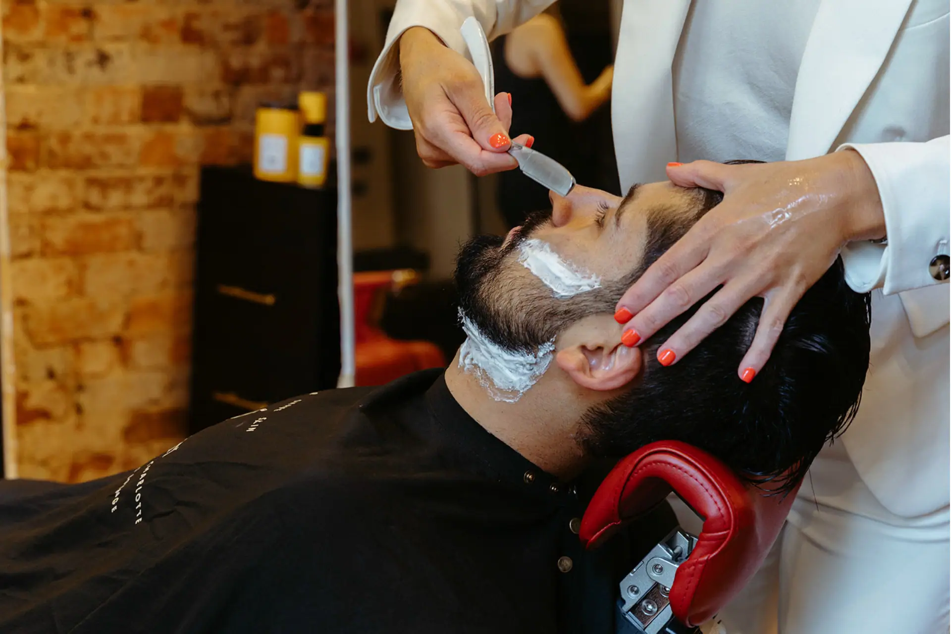 A woman shaves a man’s face as part of a men’s grooming routine