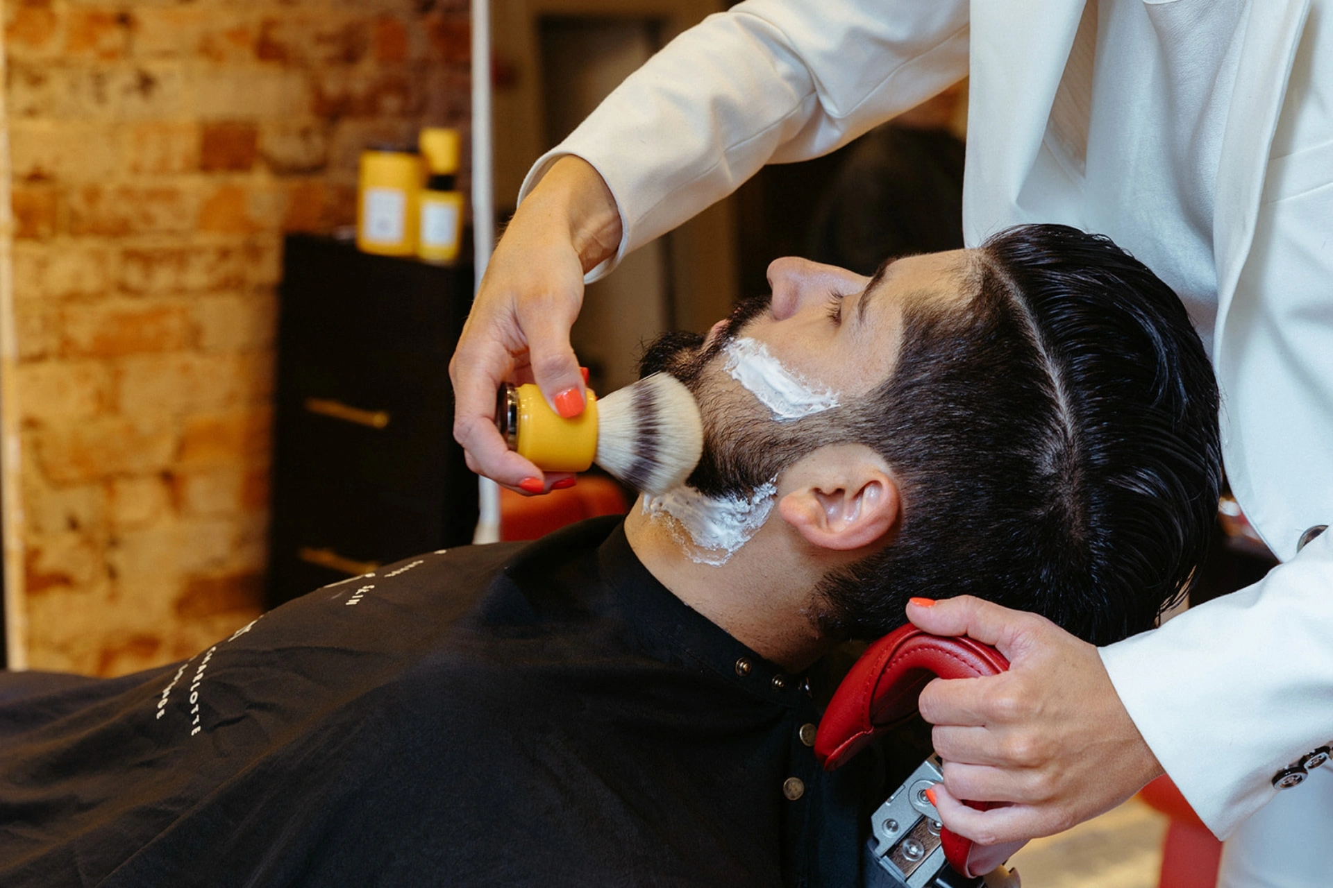 Emerson Joseph stylist using a Kabuki brush to clear a client’s face 